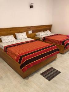 two beds sitting in a room with at Sun Rise Family Resort - Anuradhapura in Anuradhapura