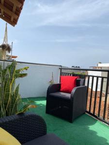 a black chair with a red pillow on a balcony at Christian Place in Praia