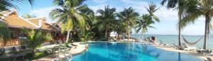 a swimming pool with palm trees and the ocean at First Villa Beach Resort in Ban Tai
