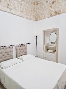 a white bedroom with a large bed and a mirror at Dimora Biancodoro in Locorotondo