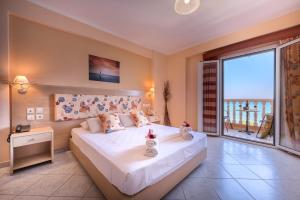 a bedroom with a large bed and a large window at Anemona Beach Hotel in Argasi
