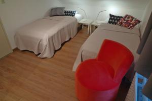 um quarto com duas camas e uma cadeira vermelha em Strandgeluk, Joost de Moorstraat 6 em Cadzand