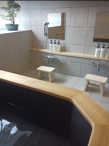 baño con bañera, espejo y 2 taburetes en Myoko Forest Lodge, en Myoko
