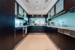 a large kitchen with dark wood cabinets and appliances at Tanaro, The Views by Emaar - Mint Stay in Dubai