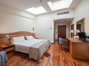 Schlafzimmer mit einem Bett, einem Schreibtisch und einem TV in der Unterkunft Hotel Il Duca d'Este in Ferrara