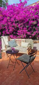 un patio con sofá, mesa y flores rosas en Lilie House, en Bormes-les-Mimosas