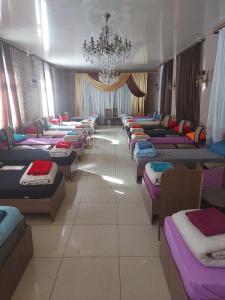eine Reihe von Betten in einem Zimmer mit einem Kronleuchter in der Unterkunft Гостиница Альянс in Qaraghandy