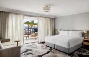 a bedroom with a bed and a chair and a window at The Beachcomber Hotel & Resort, Ascend Hotel Collection in Toukley
