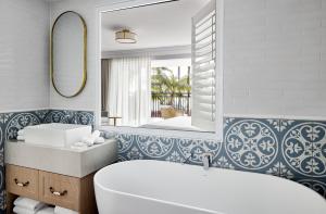 图克雷The Beachcomber Hotel & Resort, Ascend Hotel Collection的带浴缸、水槽和镜子的浴室