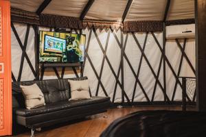 a living room with a couch in a tent at Yurt Tree, romântico e confortável, experiência unica in Jacutinga