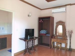 Ein Zimmer mit Fernseher, Tisch und Spiegel in der Unterkunft Phatra Hostel in Thongsala
