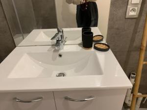 un lavandino bianco in un bagno con specchio di Le petit Cordelier a Dinan