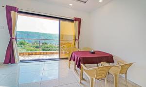 a dining room with a table and chairs and a large window at Treebo Trend Infinity View Mahabaleswar in Mahabaleshwar
