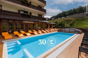 a swimming pool with orange chairs and a building at Ganz & SPA in Bukovel