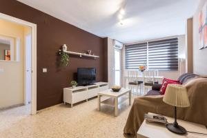 a living room with a couch and a tv at Brisas Estadio Playa Victoria in Cádiz