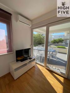 a living room with a flat screen tv and a balcony at Apartment High Five Novalja in Novalja