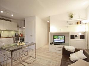 a kitchen and living room with a table and a television at Haus Meeresblick - Ferienwohnung Auszeit (Ref. 136764) in Baabe