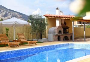 - une piscine avec 2 chaises et un parasol à côté d'une maison dans l'établissement Family cosy Vila, swimming pool, close to Nauplio, à Monastirákion