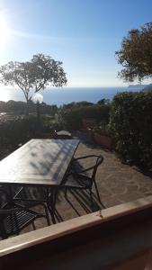 una mesa y sillas en un patio con el océano en el fondo en Fewo Sole e Azzurro, en Capoliveri