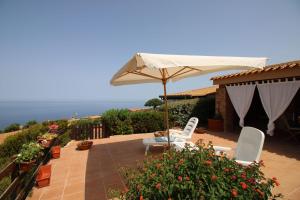 patio z 2 krzesłami i parasolem w obiekcie Casa Mira con piscina e bellissima vista mare w mieście Costa Paradiso