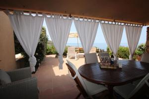jadalnia ze stołem i białymi zasłonami w obiekcie Casa Mira con piscina e bellissima vista mare w mieście Costa Paradiso