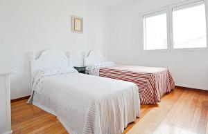 2 camas con sábanas a rayas en una habitación con ventana en Espacioso apartamento en Cambados, en Cambados