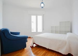 1 dormitorio con 1 cama y 1 silla azul en Espacioso apartamento en Cambados, en Cambados