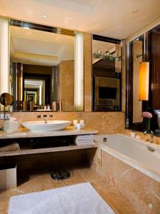 a bathroom with a tub and a large mirror at The Fullerton Bay Hotel Singapore in Singapore