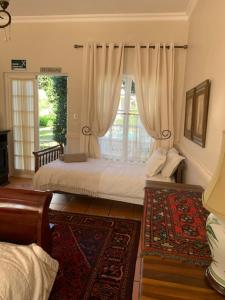 a bedroom with a bed and a window with curtains at A Tapestry Garden Guest House in Potchefstroom