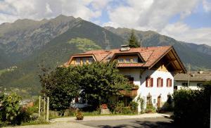 a house with a red roof in front of mountains at Krebishof Agriturismo in Schenna