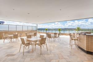 a patio with tables and chairs and a view of the water at Transamerica Lagoa Santa in Lagoa Santa