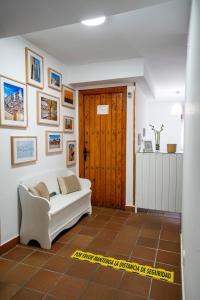 a living room with a white couch and a wooden door at Hostal Plaza de Italia in Cáceres