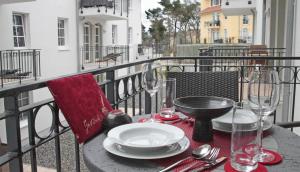 a table with plates and wine glasses on a balcony at Haus Meeresblick - Ferienwohnung Lachmoewe A 1.35 (Ref. 162722 u 1) in Baabe