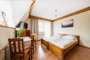 a bedroom with a bed and a table and a chair at Pokoje Gościnne Pod Łosiówkami in Poronin