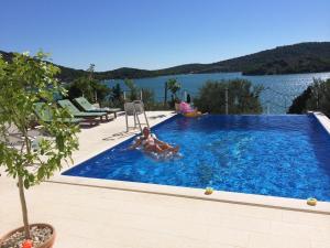 a woman laying in a swimming pool next to a lake at Villa Lana Apartments in Tisno