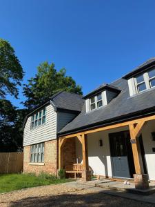 una casa con techo de gambrel y porche en Flint House - Goodwood Events en Chichester