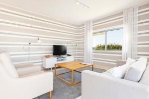 a living room with two white chairs and a television at Laguna - Vilamoura in Vilamoura