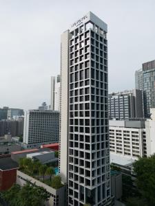 wysoki biały budynek w środku miasta w obiekcie Novotel Living Singapore Orchard w Singapurze