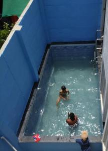 two people are swimming in a blue swimming pool at Nisarg Farm Villa in Shirdi