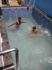 two people swimming in a swimming pool at Nisarg Farm Villa in Shirdi