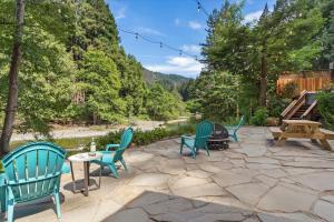 a group of chairs and tables on a stone patio at Cozy Creek Cabin - On Austin Creek Hot Tub - Dog Friendly - BBQ Grill - Fast WiFi in Cazadero