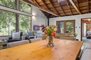 a vase of flowers on a wooden table in a room at Cozy Creek Cabin - On Austin Creek Hot Tub - Dog Friendly - BBQ Grill - Fast WiFi in Cazadero