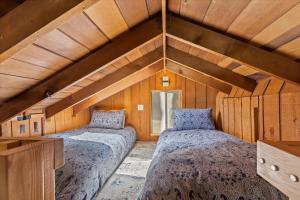 two beds in a room with wooden walls at Cozy Creek Cabin - On Austin Creek Hot Tub - Dog Friendly - BBQ Grill - Fast WiFi in Cazadero