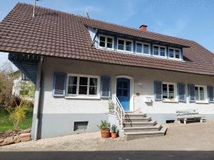 una casa blanca con una puerta azul y escaleras en Ferienwohnung Reinbold, en Durbach