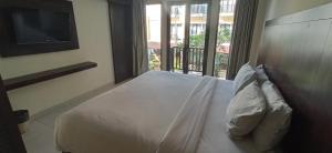 1 dormitorio con cama blanca y balcón en Suris Boutique Hotel, en Kuta