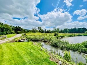 a river with a boat in a grassy field at THE HAYLOFT CHESHIRE in Congleton