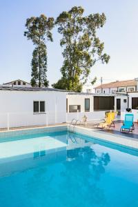 a swimming pool with two chairs next to a building at Live, Laugh, Love Beach Guest Home with AC in Madalena