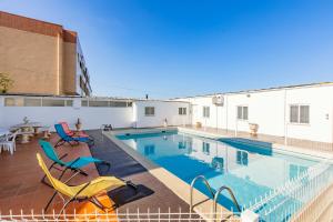 a swimming pool with two chairs and a table at Live, Laugh, Love Beach Guest Home with AC in Madalena