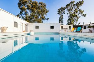 a swimming pool with blue chairs next to a building at Live, Laugh, Love Beach Guest Home with AC in Madalena