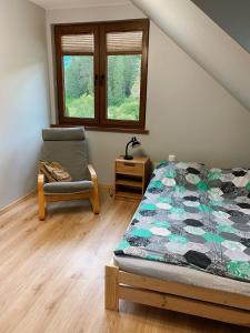 a bedroom with a bed and a chair and windows at Świerkowe Domki Cisna in Cisna